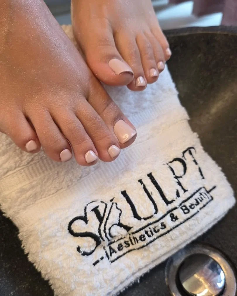 Fresh nude pedicure resting on a Skulpt-branded towel