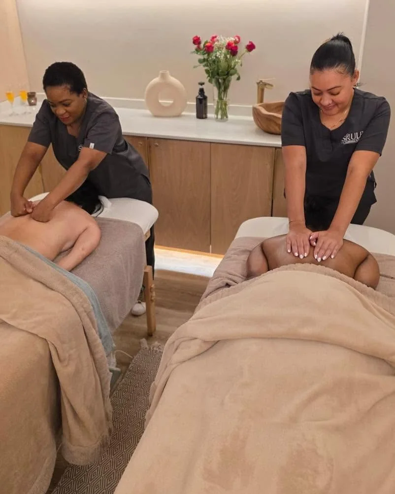 Two therapists giving back massages during a couples spa session at Skulpt